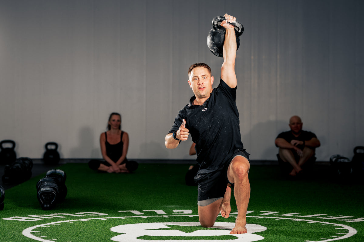 Kettlebell demonstration in a half-kneeling position during a group training session